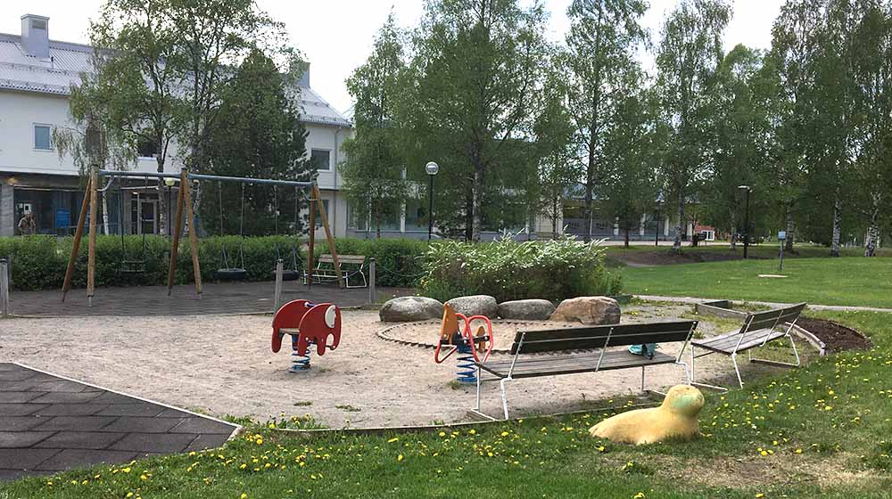 Gungleksaker i sandyta och en stenfigur i form av en säl i gräset att rida på