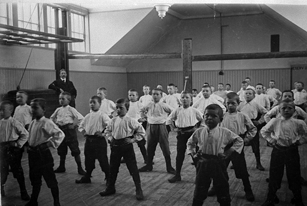 Småpojkar i gymnastiksal stående bredbent med händerna i sidorna.